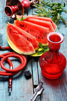 Still life with slices of ripe watermelon and smoking hookah