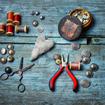 Scissors ,iron, stylish old-fashioned buttons and thread on wooden background