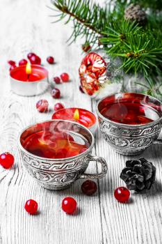 Cranberry tea in stylish iron cups at the Christmas background