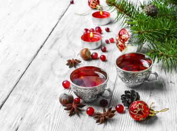 Cranberry tea in stylish iron cups at the Christmas background