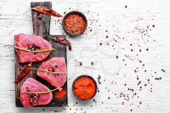 Three raw chops veal steak with peppers and spices