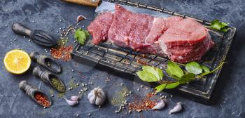 Raw beef steak and laurel branch on cutting board