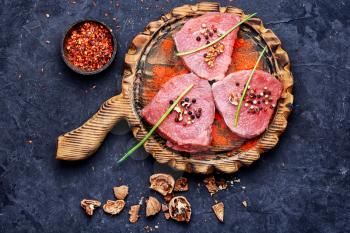 Raw beef steak with spices and walnuts on the kitchen board