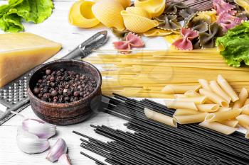 Large selection of uncooked spaghetti and macaroni on the kitchen table with ingredients