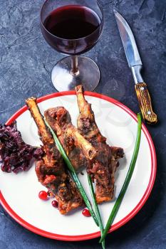 Dish of lamb chops baked in spices and glass of red wine