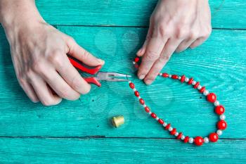 Create fashionable necklaces from beads with their hands