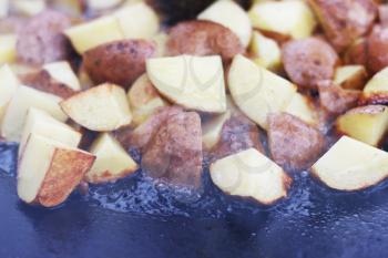 Frying raw potato in sunflower oil on large pan. Cooking potatoes