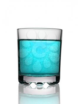 Glass with blue fizzy cocktail on white background with reflection, studio shot