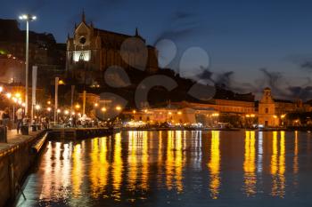 Night cityscape with lights reflected in sea water. Gaeta town, Italy