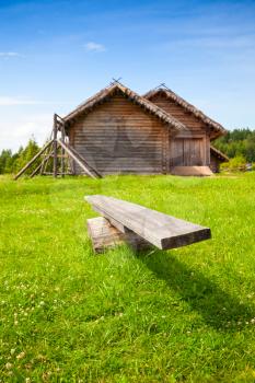 Old wooden swing stands on bright green grass in Russian village