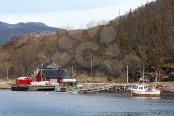 Traditional small Norwegian village with red wooden houses and small fishing boat nearby