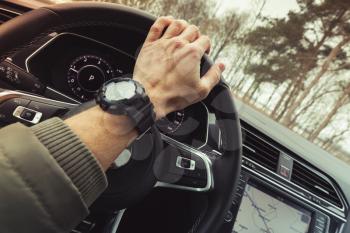 Driver hand holds steering wheel of luxury crossover car. Close-up photo with selective focus and warm tonal correction filter effect