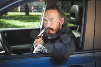 Serious Asian man smoking pipe. Driver of modern Japanese crossover suv car, portrait in open car window