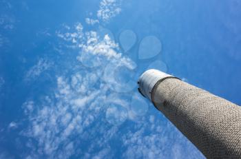 Tall water tower made of gray bricks with steel tank on top over cloudy blue sky background