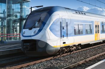 Electric passenger train goes near railway platform in Amsterdam, Netherlands