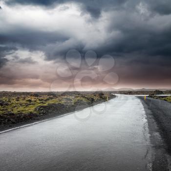 Empty rural road under dark dramatic stormy sky, Reykjavik district, Iceland