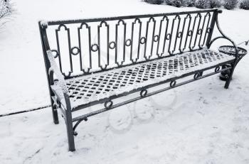 Outdoor metal bench covered with snow in winter park. St-Petersburg, Russia