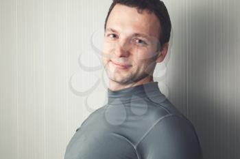 Studio portrait of young smiling European man in gray sportswear
