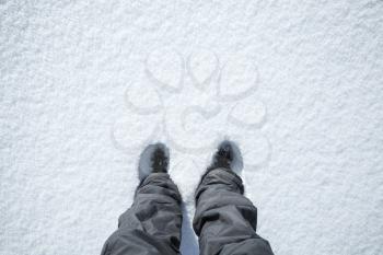 Feet stand in fresh snow, top view, winter walking