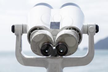 Binocular telescope on a rotating base mounted on an outdoor touristic viewpoint, front view