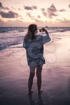 Teenage girl makes selfie photo on the beach in early morning. Dominican Republic, Punta Cana