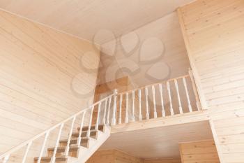 Empty wooden house interior with stairway going up to second floor