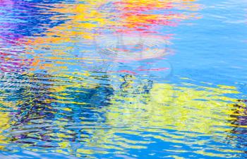 Colorful reflections over ripple water surface. Abstract background photo texture