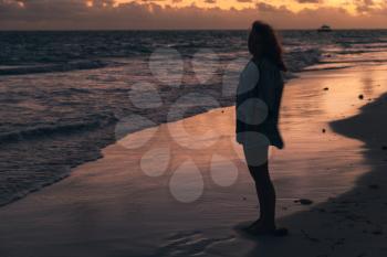 Silhouette photo of a girl walking on the ocean coast in morning. Sunrise over Atlantic ocean, Dominican Republic, Bavaro beach