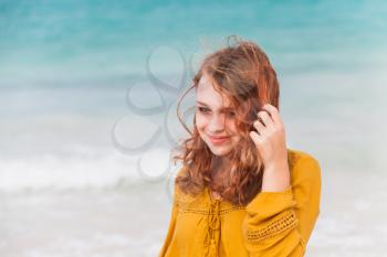 Outdoor portrait of smiling Caucasian teenage girl with red hair on the ocean coast in Dominican Republic