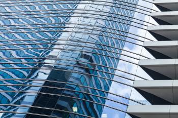 Abstract modern office building architecture fragment, walls of glass and steel with reflections of blue cloudy sky