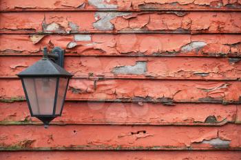 Street lamp mounted on grungy red wooden wall