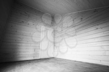 White door in the corner of empty room. Wooden house interior. Black and white photo