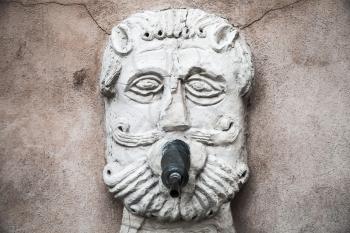 Ancient fountain with drinking water in the shape of a bearded male face. Fermo, Italy