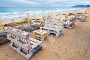 Standard white furniture made of wooden cargo pallets, cheap seaside terrace. Porto Santo island, Madeira archipelago, Portugal