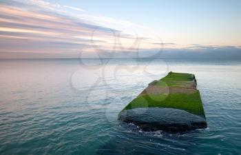 Old stone pier with green grass. Black Sea coast. Russia, Sochi, Adler