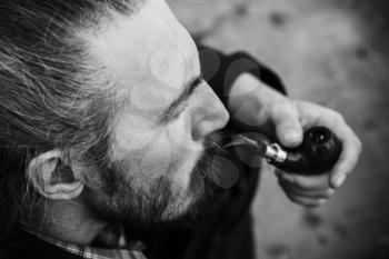 Bearded man smokes a pipe, black and white face portrait with selective focus