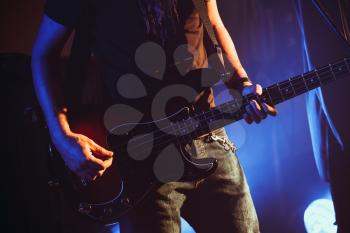 Rock music theme, electric bass guitar player, closeup photo with soft selective focus