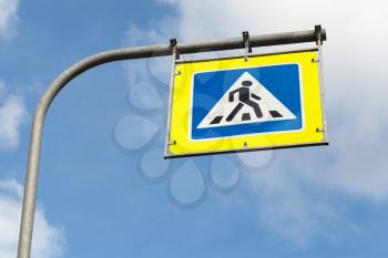 Pedestrian crossing. Square blue and white road sign with yellow frame over blue sky background