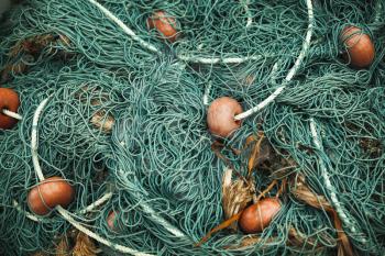Green fishing net with red floats lays in port. Close-up background photo with selective focus