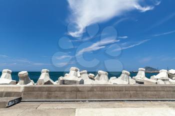 Breakwater structure with concrete blocks under cloudy sky in sunny day. Industrial background photo