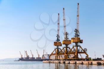 Yellow cargo port cranes stand on the pier in Burgas harbor. Black Sea coast, Bulgaria