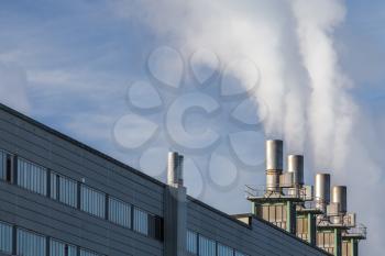 Facade of industrial building with smoking chimneys