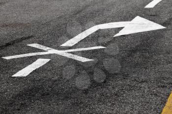 Right turn is prohibited. Crossed white arrow, road marking on dark asphalt. Close-up photo with selective focus