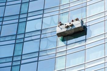 Office building maintenance, blue glass facade cleaning with cradle