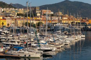Ajaccio port in morning sunlight. Coastal cityscape with sailing yachts and pleasure motor boats moored in marina, Corsica island, France