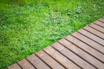New wooden boardwalk over lawn with green grass, modern park background, top view