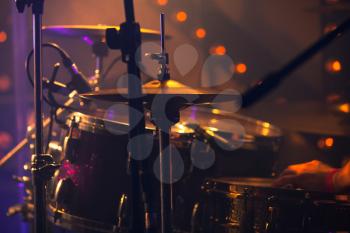 Rock music background, drummer plays with drumsticks on rock drum set. Warm toned close-up photo, soft selective focus