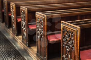 Old wooden prayer benches with carving in a row.  Bath Abbey. Bath, Somerset, UK