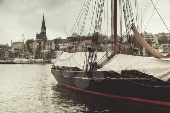 Sailing ship moored in old port of Flensburg, Germany. Vintage stylized photo with tonal filter effect