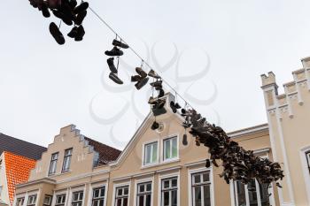 Abandoned sporty shoes hang on electric wire over urban road, street view of old Flensburg, Germany